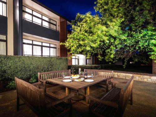 a wooden table with two chairs and a tableasteryasteryasteryasteryasteryasteryastery at The Sebel Bowral Heritage Park in Bowral