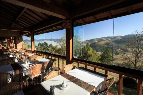 a restaurant with tables and chairs and large windows at Pousada do Quilombo in São Bento do Sapucaí