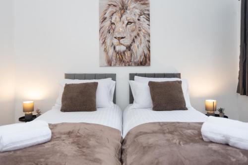 two beds in a bedroom with a lion painting on the wall at Wellington - Telford house - With parking in Wellington