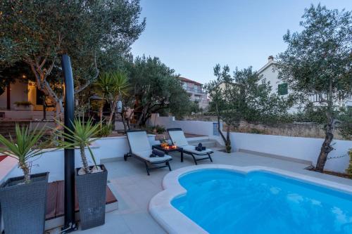 een patio met een zwembad, stoelen en bomen bij Komplex Oliva Mit Pool Und Großem Garten in Stari Grad