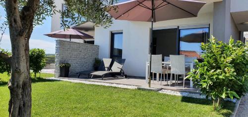 een huis met een patio met stoelen en een parasol bij Apartment Elegance in Krk