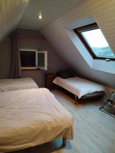 a attic bedroom with two beds and a window at Féerie de la Vigne in Ammerschwihr