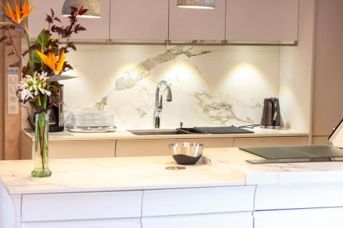 - un comptoir de cuisine avec un évier et un vase de fleurs dans l'établissement Les gîtes de Lanevry 800m plage, à Kerlaz
