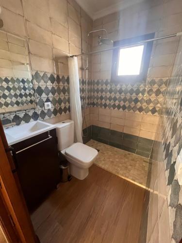 a bathroom with a toilet and a sink and a window at Chalet Playa Paraiso in Cádiz