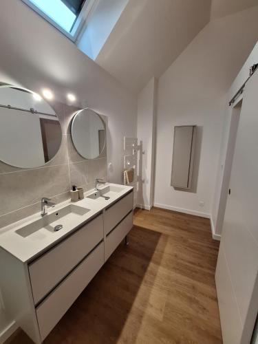 a white bathroom with two sinks and two mirrors at Gite en Champagne in Vertus