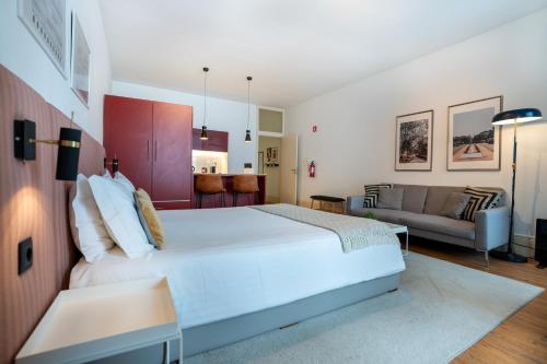 een slaapkamer met een groot wit bed en een bank bij Calacatta Housing in Porto