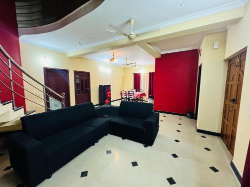 ein Wohnzimmer mit einem schwarzen Sofa und einer roten Wand in der Unterkunft Texas 3 BHK villa for 13 pax near Airport in Thiruvananthapuram