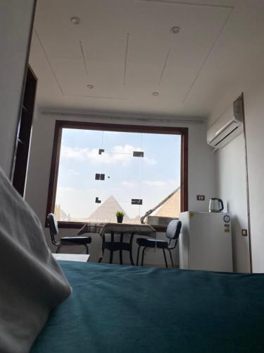 a room with a table and chairs and a large window at Pyramids Fort & free pickup shuttle in Cairo