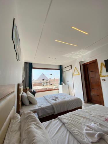 two beds in a hotel room with a window at Pyramids Fort & free pickup shuttle in Cairo