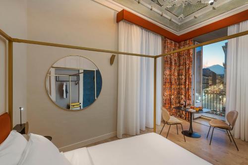 a bedroom with a bed and a mirror and a window at Belduomo Catania Rooms & Flat in Catania