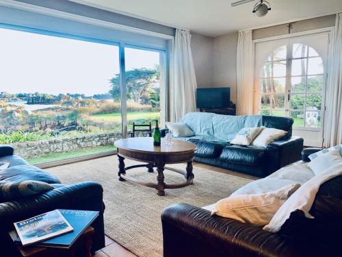 ブレアにあるSt Rom, Vue imprenable sur l'Ile de Bréhatのリビングルーム(ソファ、テーブル付)、大きな窓が備わります。