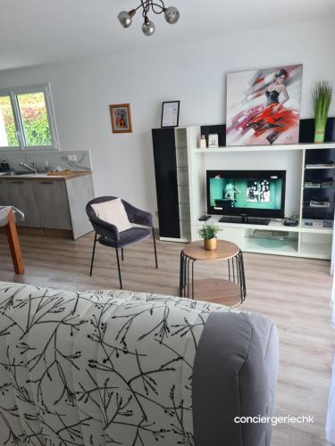 ein Wohnzimmer mit Fernseher, Couch und Tisch in der Unterkunft Chez Tina jolie maison à 12 min du Puy du Fou in Les Herbiers