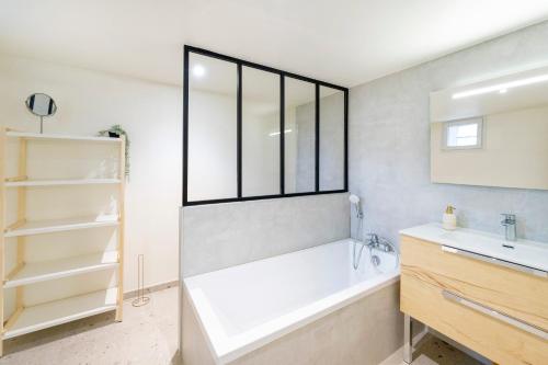 a bathroom with a bath tub and a sink at Séjour Entre Océan et Centre-Ville in Hossegor