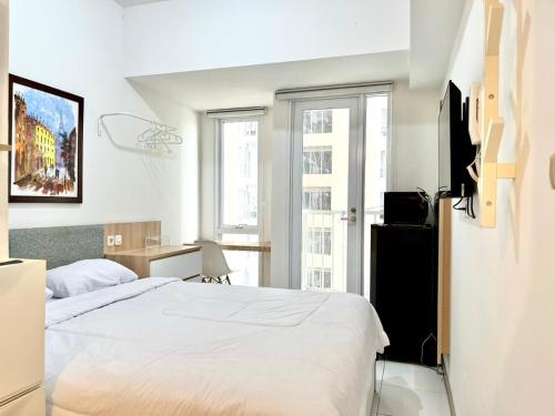 ein Schlafzimmer mit einem weißen Bett und einem Schreibtisch in der Unterkunft Apartment Tokyo Riverside By Seagull Luxury Apartment in Gedong