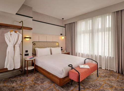 ein Hotelzimmer mit einem Bett und einem Kleid, das in einem Fenster hängt in der Unterkunft The Grand Hotel Leicester by The Unlimited Collection in Leicester