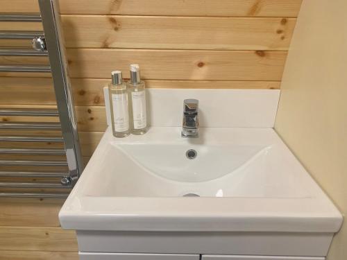 un lavabo de salle de bain avec deux bouteilles dessus dans l'établissement Willowbrook Luxury Log Cabin with private hot tub, à Kings Norton