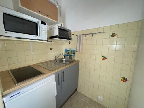 a small kitchen with a sink and a microwave at Le Pignon - TV, 1min de la Mer, Central in Saint-Jean-de-Monts