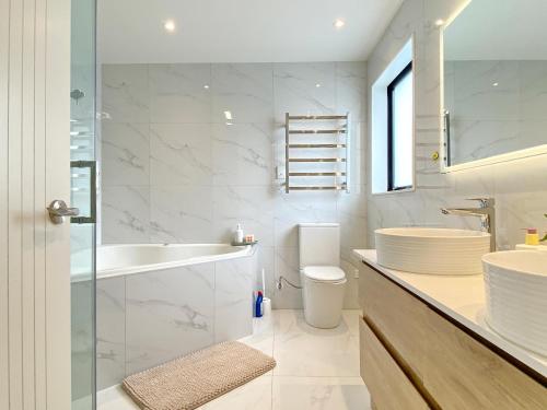 a white bathroom with a sink and a toilet at Spacious 7 BRs 4 BHs house on Longhorn, Flat Bush in Auckland