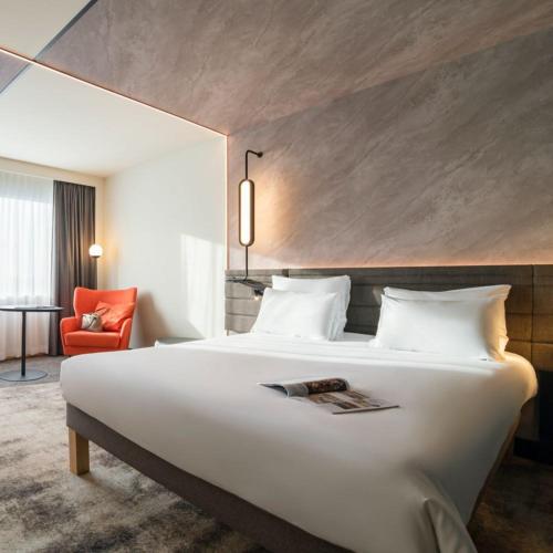 a hotel room with a large bed and a red chair at Novotel London Paddington in London