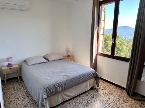 a bedroom with a bed and a large window at Maison de Charme Vue Exceptionnelle Mer & Montagne in Campomoro