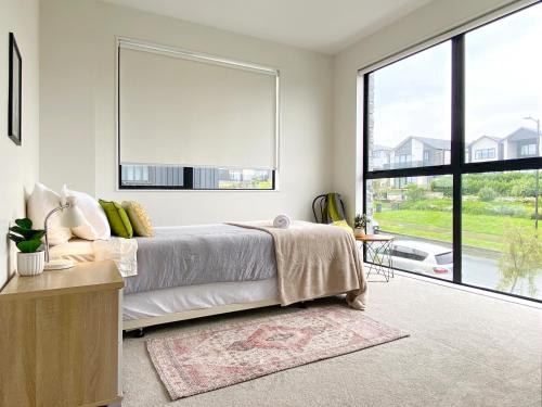 a bedroom with a bed and a large window at Spacious 7 BRs 4 BHs house on Longhorn, Flat Bush in Auckland