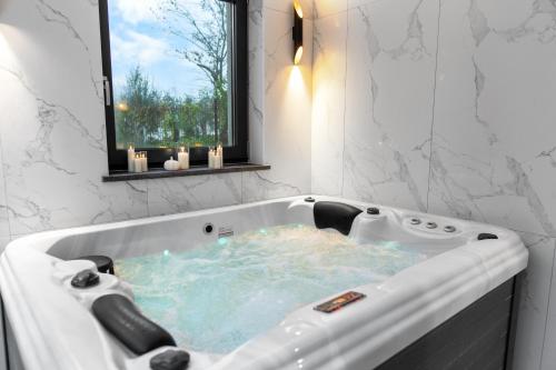 een badkamer met een bubbelbad en een raam bij Charming Villa Harmonia with Heated pool and Indoor Jacuzzi surrounded by nature in Pićan