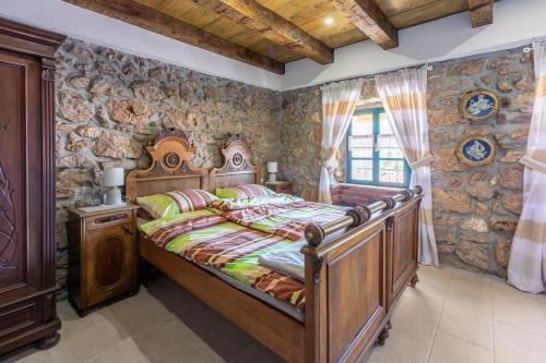 a bedroom with a wooden bed and a stone wall at Paun in Bribir