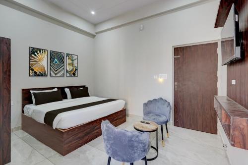 a bedroom with a bed and two blue chairs at Collection O Kesar Crossway Jaipur Formerly Laxmi Palace in Jaipur