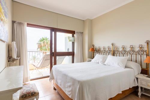a bedroom with a white bed and a balcony at Primera línea de playa Marbella in Marbella