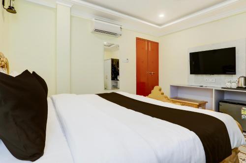 a bedroom with a large white bed and a flat screen tv at Palette Heritage Varanasi Retreat in Varanasi