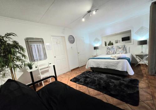 een slaapkamer met een bed, een spiegel en een bank bij Zhantique Guest House 1- Unit 5 in Boksburg