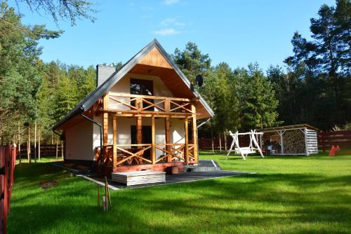 a small house in a yard with a playground at Domek Sosenka Roztocze Hutki in Krasnobród
