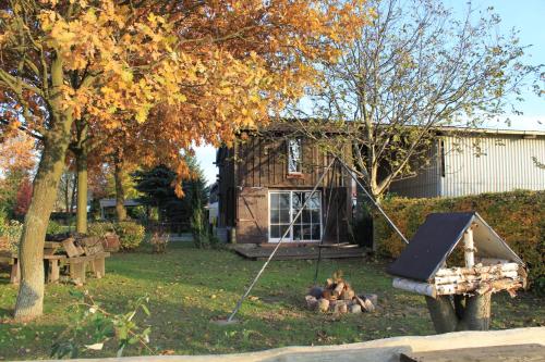 a playground in front of a house with a tree at Ferienhaus Am See In Blankensee Groß Schönfeld in Blankensee