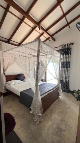 a bedroom with a bed with a mosquito net at Mirewon Guest in Weligama