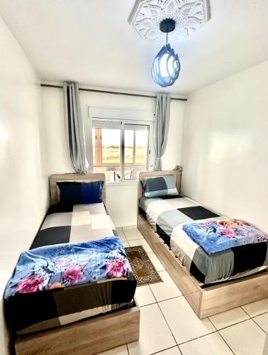 two beds in a bedroom with a window at Apprt cosy près plage des Nations in Salé