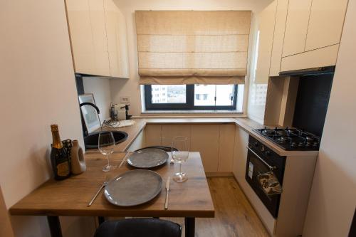 eine kleine Küche mit einem Holztisch mit Weingläsern in der Unterkunft Contemporary 1-Bedroom Oasis in Pipera - Ivory Residence in Bukarest