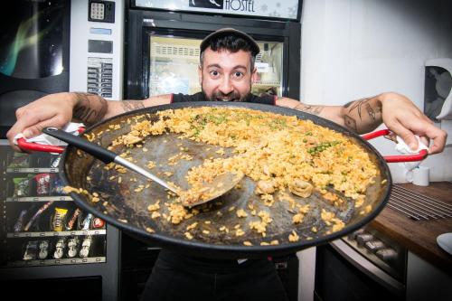 a man holding a pan full of food at Black Swan Hostel in Barcelona