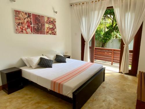 a bedroom with a bed and a large window at Lake House Hikka in Hikkaduwa