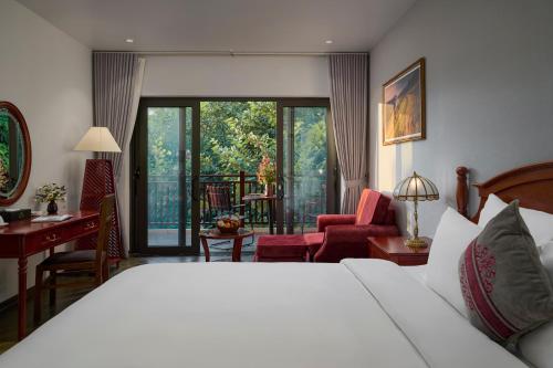 Una habitación de hotel con una cama y un escritorio y una habitación. en Sơn Nữ Emerald Hill Hotel, en Bak Kan