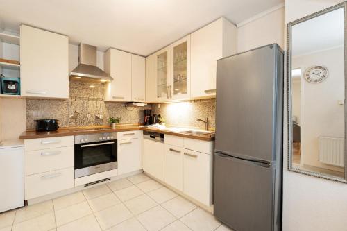 a kitchen with white cabinets and a stainless steel refrigerator at Heckenröschen in Grömitz