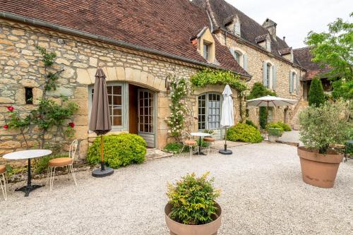 einen Innenhof mit Tischen und Sonnenschirmen vor einem Gebäude in der Unterkunft La Tour de Cause in Castelnaud-la-Chapelle