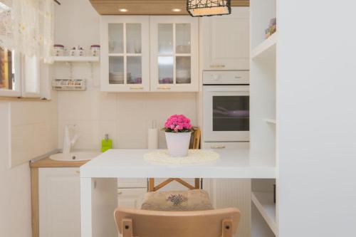 a kitchen with white cabinets and a table with a vase of flowers at Dalmatinisches Haus In Der Altstadt Von Split in Split