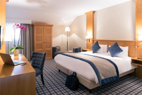a hotel room with a bed and a desk with a laptop at Mercure Luxembourg Kikuoka Golf & Spa in Canach