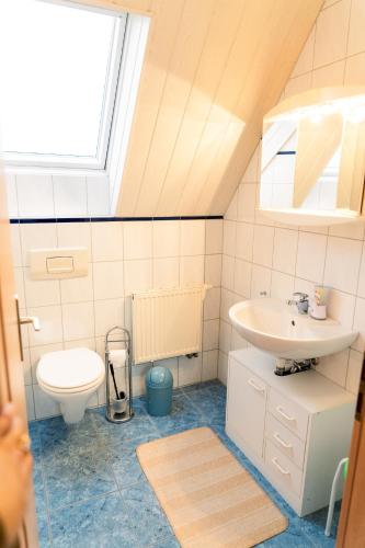a bathroom with a sink and a toilet and a window at Heimliche Liebe - Ferienhaus in Südbrookmerland