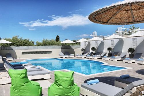 a resort pool with lounge chairs and an umbrella at Elounda Garden Maxima Suite Beheiztes Schwimmbad in Elounda