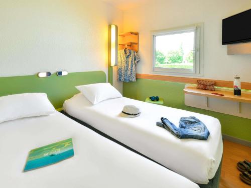 a bedroom with two beds with a television and a window at ibis budget Clermont Ferrand Sud in Aubière