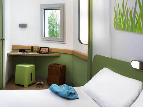 a small room with a bed and a desk with a window at ibis budget Chambéry Sud Challes Les Eaux in Challes-les-Eaux