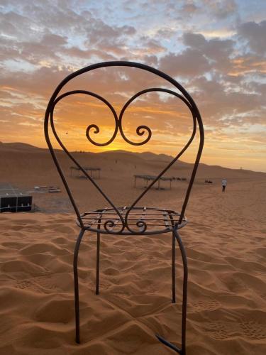 a chair sitting in the sand in the desert at Merzouga nights tents in Merzouga