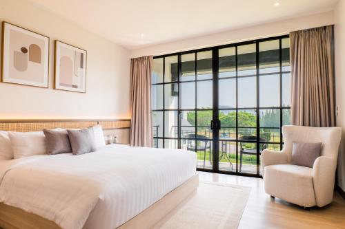 ein Schlafzimmer mit einem großen Bett und einem Stuhl in der Unterkunft Estella Khao Yai in Khao Yai