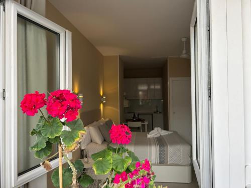 a room with a bed and a window with red flowers at Carihuela Beach Apartamentos in Torremolinos